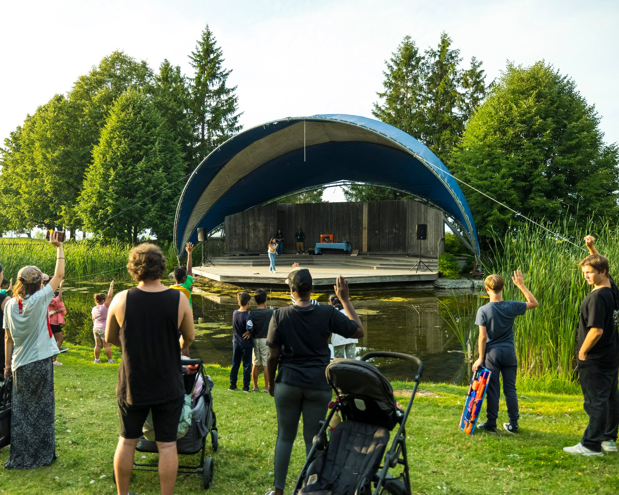 A crowd worshiping with raised hands at an outdoor revival gathering